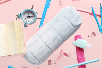 Flying pencil case and school stationery on pink background, closeup