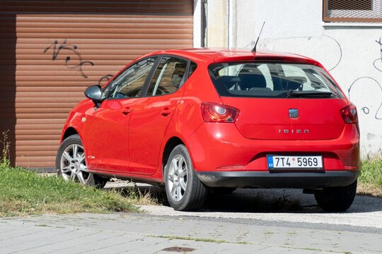 Red Seat Ibiza hatchback car parked in front of a garage