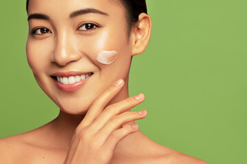 Facial cream smear. Hydration and skin care concept. Young beautiful asian model posing with...