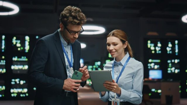 Information technology specialists working tablet at night datacenter closeup