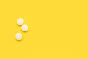 White medical pills on yellow background - obrazy, fototapety, plakaty