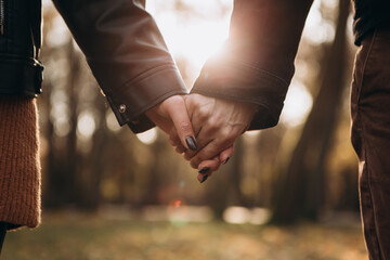 Cropped image hands young loving couple pinky swear, pinky promise hook each other's little finger, hugging smiling kissing laughing spending time together. Autumn, fall season, maple leaves - obrazy, fototapety, plakaty