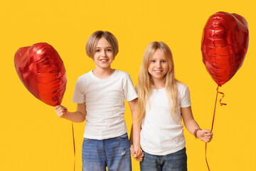 Little children with heart-shaped balloons holding hands on yellow background. Valentine's Day...