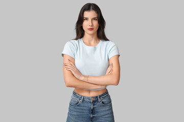 Young woman with crossed arms on grey background. Feminism concept