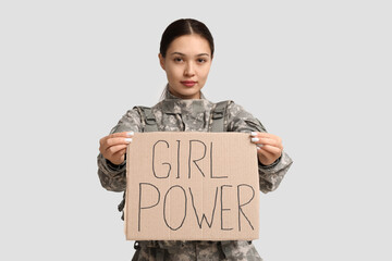 Young female soldier with sign GIRL POWER on white background. Feminism concept