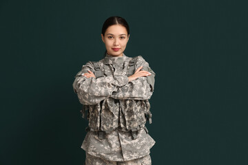 Young female soldier with crossed arms on green background. Feminism concept