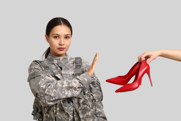 Young female soldier rejecting high heel shoes on white background. Feminism concept