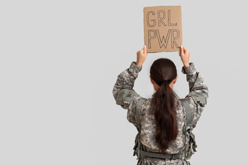 Young female soldier with sign GRL PWR on white background, back view. Feminism concept