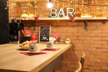 Bar counter with cups of hot chocolate, hearts and glowing lights, closeup. Valentine's Day...