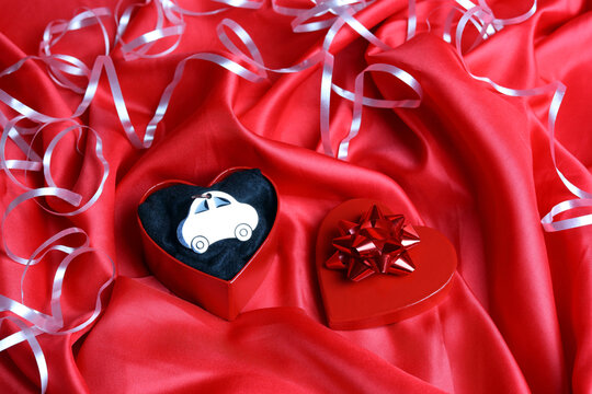 a car keyring in a heart shaped gift box sitting on red silk