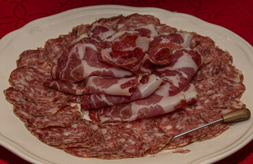 Sliced Salami and Soppressata Arranged on White Plate over Red Tablecloth