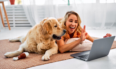 Gadgets for conversation. Positive female resting on floor with furry friend and using wireless...