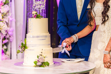 Indian couple's cutting a wedding cake hands close up