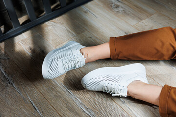 Close-up of female legs in white perforated leather sneakers. Women's summer sneakers. Collection...