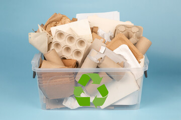 Separate collection of paper garbage in a plastic box on blue background. Stuff for recycle. Eco friendly concept. Isolated recyclable paper waste: cardboard, egg carton, disposable cup, paper sleeve