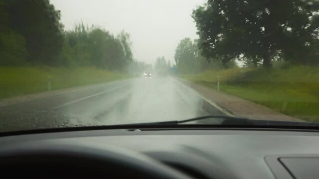 Rainy road trip: Person driving with active wipers in heavy rain