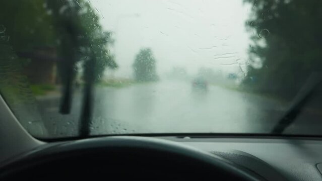 Weathering the storm: Car wheel view during heavy rainfall with active wipers