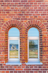 Ancient red brick wall, daylight, with two arched windows. Vertical photo