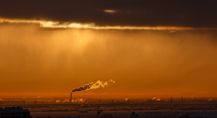 Plumes of factory smoke rise from the chimneys into the sky at sunset. The chimney emits exhaust gases into the sky. The concept of air pollution and the environment.	