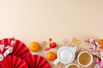Chinese New Year tea ceremony idea. Top view shot of teapot, cups of tea, tangerines, folding fans, sakura, gold coins on beige background with promo space