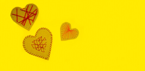 A hearts made of cardboard and thread on a yellow background. Valentine's day ideas are simple for...