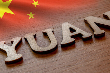Chinese yuan concept, yuan word concept made of wooden letters on wooden background with Chinese flag
