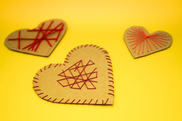 A hearts made of cardboard and thread on a yellow background. Valentine's day ideas are simple for kids.