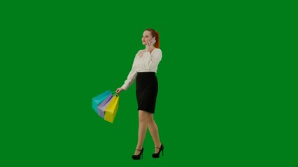 Portrait of attractive office girl on chroma key green screen. Woman in skirt and blouse walking talking on smartphone, positive face expression. Half turn.