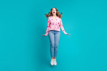 Fototapeta na wymiar Full body length photo of overjoyed young beautiful lady jumping high wear glamour cardigan and jeans isolated on blue color background