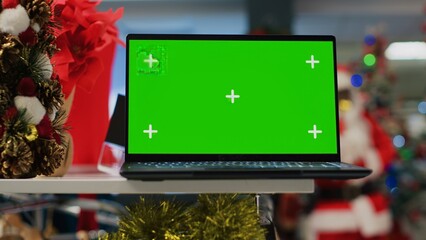 Chroma key laptop on Christmas decorated clothing store display table showing information about...