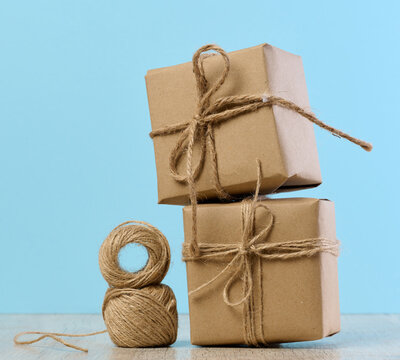 The box is packed in brown craft paper and tied with a rope on a blue background, gift