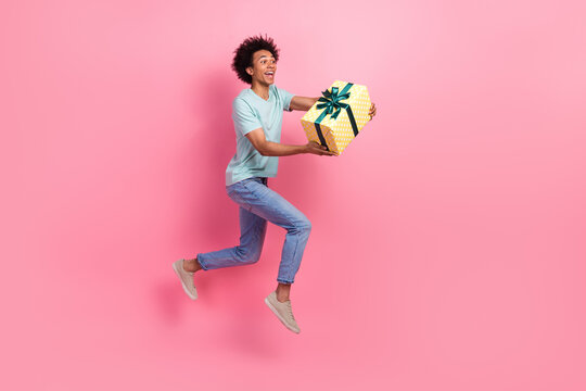 Full size photo of nice young guy running fast shopping christmas gifts sales dressed stylish blue outfit isolated on pink color background