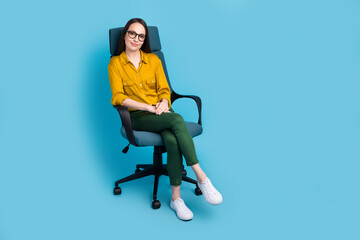 Fototapeta na wymiar Full length photo of sweet good mood lady wear yellow shirt spectacles sitting chair empty space isolated blue color background