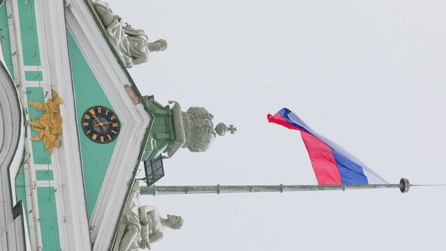 the Russian flag on the building of the Winter Palace is waving in the wind in a snowfall, the crown of the Russian Empire on a bas-relief