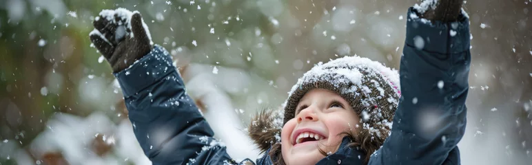 Fotobehang Happy kid wearing warm clothes plays outdoors with snow in winter. © PixelGallery