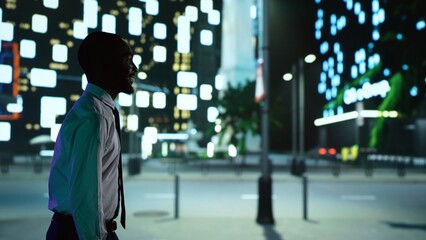 African american person on night walk downtown under streetlights, admiring modern office buildings...