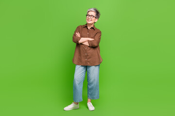 Full size photo of good mood person wear stylish shirt arms folded look at proposition empty space isolated on green color background