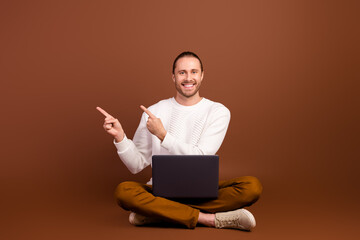 Full length photo of positive funky man wear white sweater texting modern device showing empty space isolated brown color background