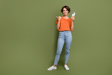 Full length photo of adorable smart girl in eyewear hold smartphone indicating at offer empty space...