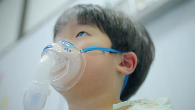 A little boy having a medicine inhalation with a nebulizer mask in the hospital.
