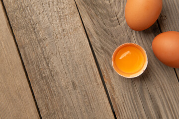 Top view of egg yolk in eggshell on wooden table with copy space