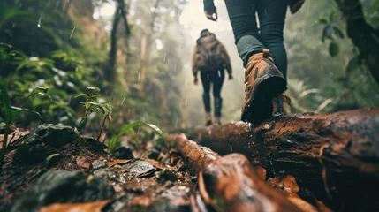 Fotobehang Jungle Challenge: In a low angle shot, an Asian couple attempts to climb over a log in a raining jungle, with the focus on their trekking shoes in this adventurous and challenging trek.   © Mr. Bolota