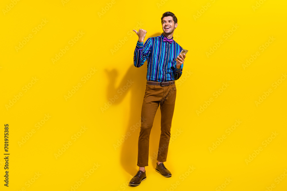 Poster full body photo of optimistic man wear bow tie hold smartphone look directing at offer empty space i
