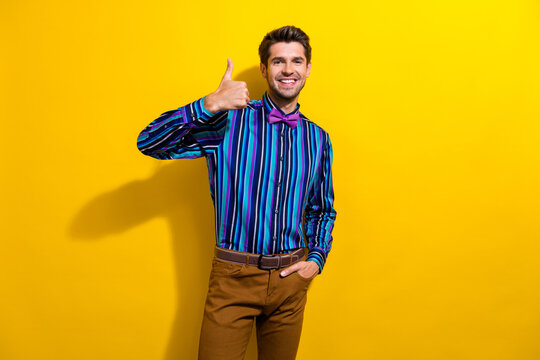 Portrait of satisfied nice guy dressed stylish shirt bow tie show thumb up good job isolated on vibrant yellow color background