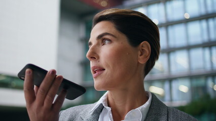 Company executive recording voice message on smartphone. Serious woman send mail