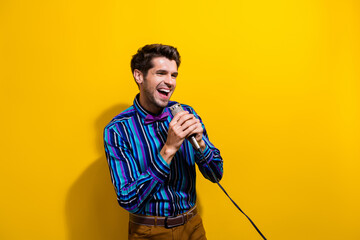 Photo of good mood handsome man dressed striped shirt bow tie holding microphone look empty space...