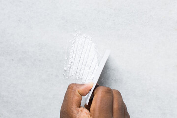 Top view of brown hand cutting lines of cocaine with a white card, concept photo of drug abuse