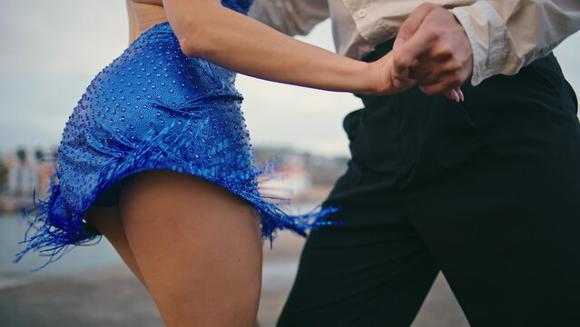 Closeup woman dancer hips moving energetic in blue dress outside. Couple dancing