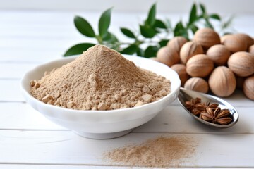 Nutmeg powder with seeds in a bowl on a white table