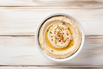 Obraz na płótnie Canvas Top view of homemade hummus on white wooden background